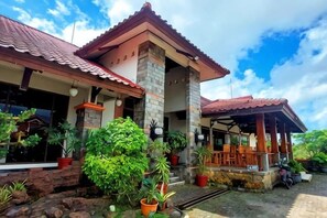 A house with a tiled roof, stone pillars, and a porch with chairs. - Sanggabuana Puncak Convention & Resort (Pacet)