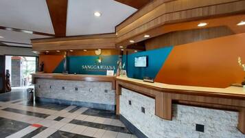 A reception area with a reception desk, a counter, and a wall-mounted screen.