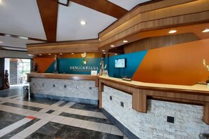 A reception area with a reception desk, a counter, and a wall-mounted screen. - Sanggabuana Puncak Convention & Resort (Pacet)