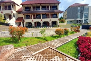 A multi-story building with a central courtyard, a patterned walkway, and a variety of plants. - Sanggabuana Puncak Convention & Resort (Pacet)