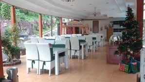 A restaurant with white chairs and tables, a Christmas tree, and a sign reading "CILOTO INDAH PERMAI". - Hotel Ciloto Indah Permai (Cipanas)