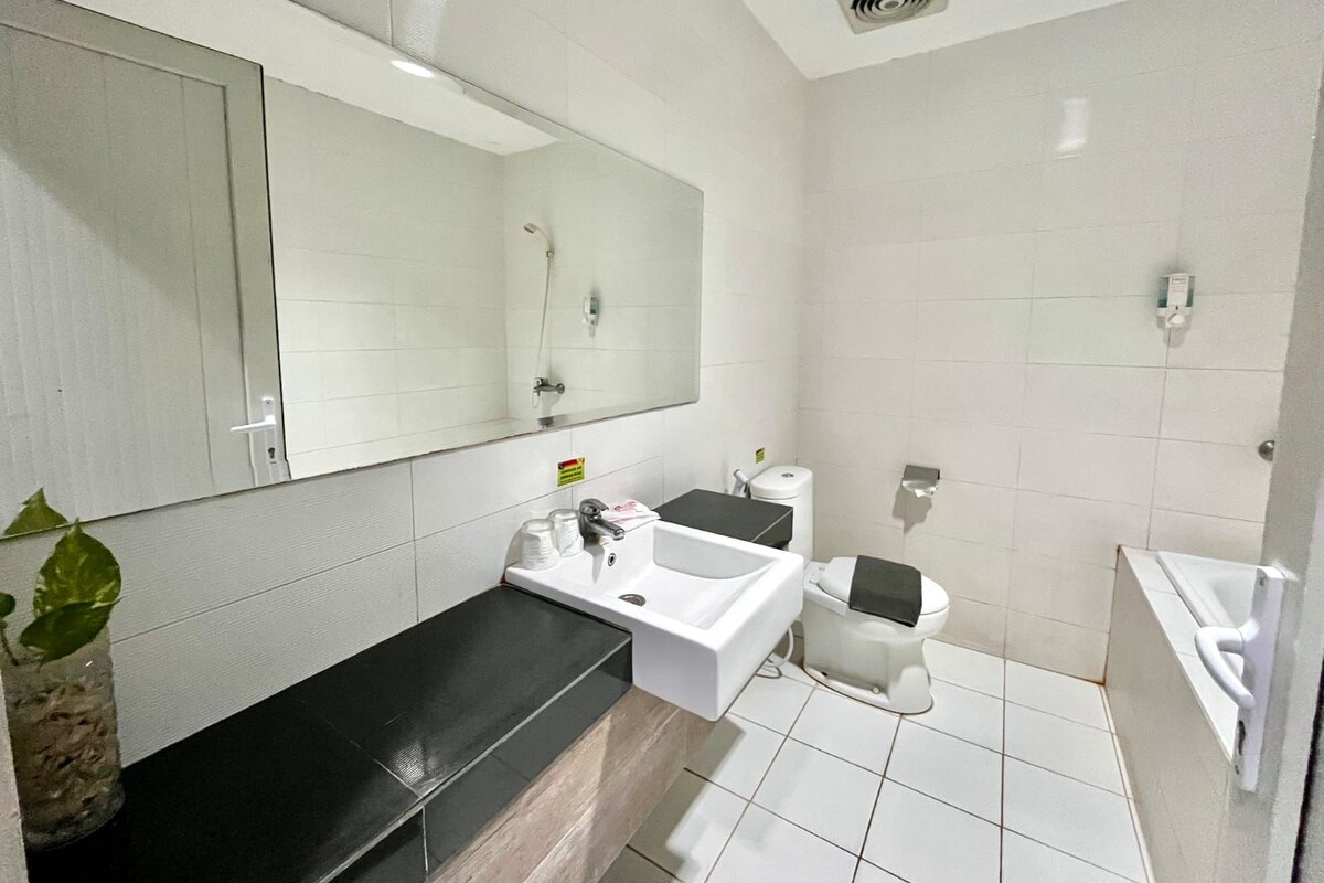 Un baño moderno con un espejo grande, un lavamanos, un inodoro y una ducha.