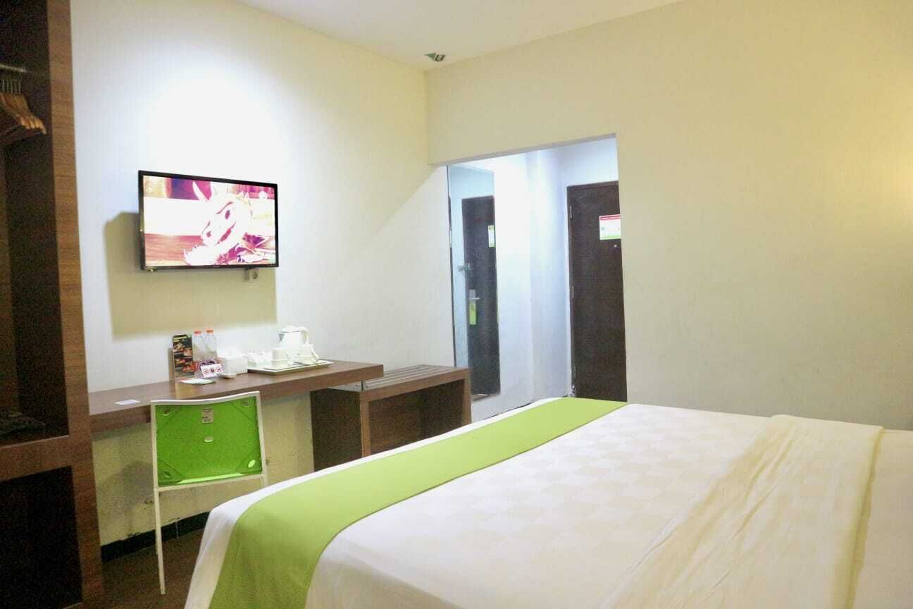 Een hotelkamer met een bed, een bureau, een stoel, een televisie en een deur.