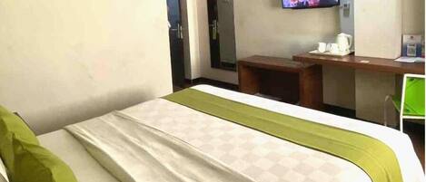 Una habitación de hotel con una cama, un escritorio, un televisor y una puerta.