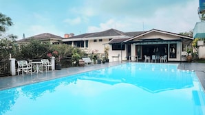 A swimming pool with lounge chairs and a covered patio area. - Resort Prima Coolibah Puncak (Cipanas)