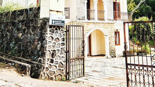 A two-story building with a reception area, stone wall, and a gated entrance. - Resort Prima Coolibah Puncak (Cipanas)