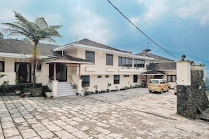 A two-story building with a restaurant and reception area, paved driveway, and parked vehicles. - Resort Prima Coolibah Puncak (Cipanas)
