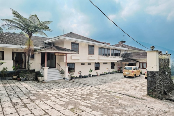 A two-story building with a restaurant and reception area, paved driveway, and parked vehicles.