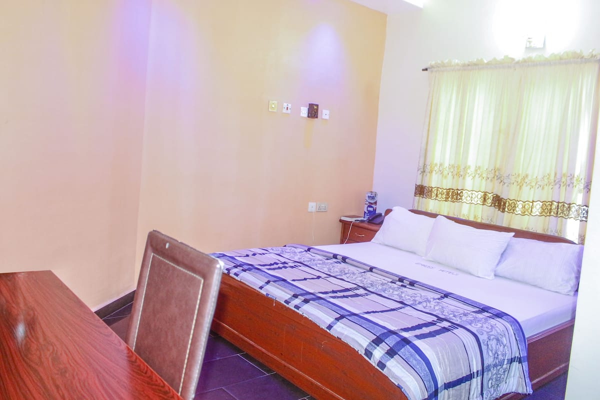 A bedroom with a wooden bed, a bedside table, and a chair.
