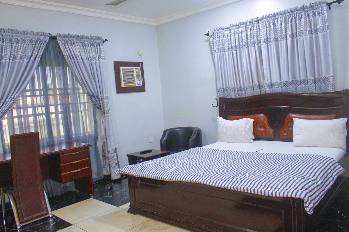 A bedroom with a wooden bed, a desk, and a chair.