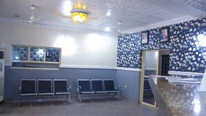 Un área de espera con un mostrador de recepción, una araña de cristal y una pared con diseño.