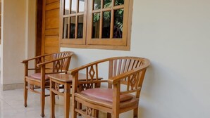 Un juego de sillas de madera y una mesa frente a una pared con ventanas.