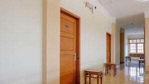 Un pasillo con puertas de madera, una mesita y un banco.