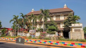 Un hotel grande de varios pisos con estilo arquitectónico tradicional, que cuenta con una entrada destacada con un borde colorido y un cartel.