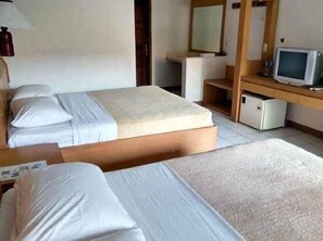 Habitación de hotel con dos camas, un escritorio, un televisor y un espejo.