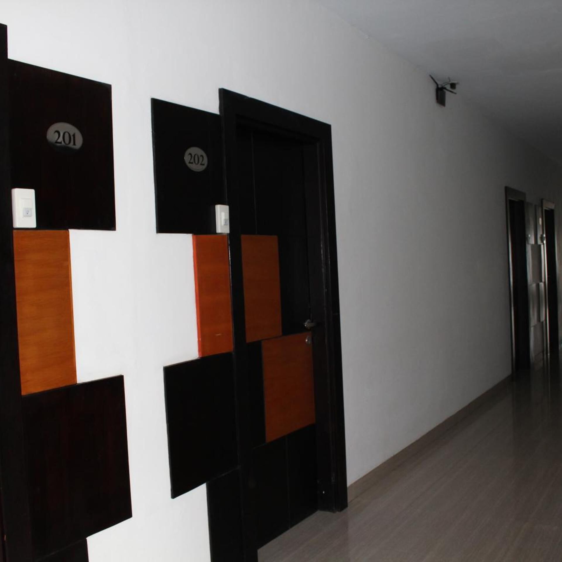 A hallway with doors numbered 201 and 202, wooden floor, and a light fixture on the ceiling.