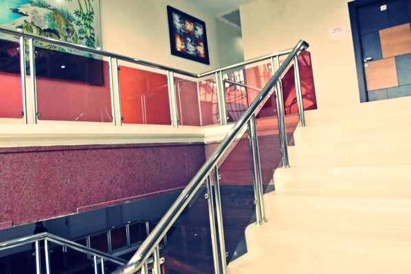 Una escalera con barandillas de metal y una pared roja.