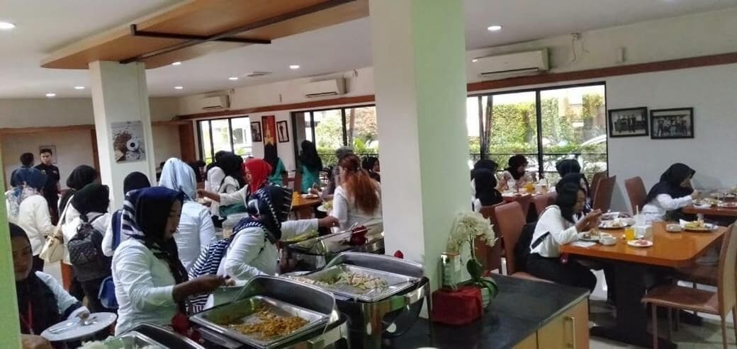 A cafeteria with multiple tables and people dining.