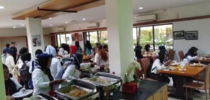 A cafeteria with multiple tables and people dining.