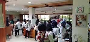A reception area with a counter, a clock, and a 'No Smoking' sign. - Hotel Grand Karawang Indah (Karawang)