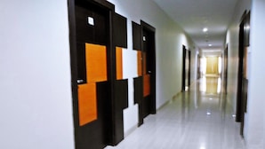 A long, narrow hallway with doors on one side and a plain wall on the other. - Hotel Grand Karawang Indah (Karawang)