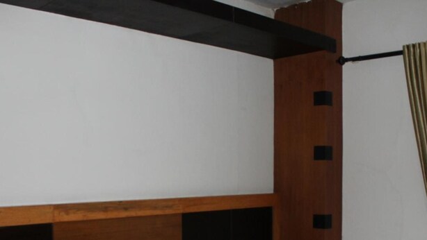Habitación de hotel con cama, cabecero de madera, ropa de cama blanca y un plaid a rayas.