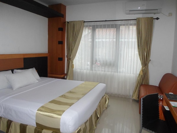 A hotel room with a bed, a desk, a chair, and a window with curtains.