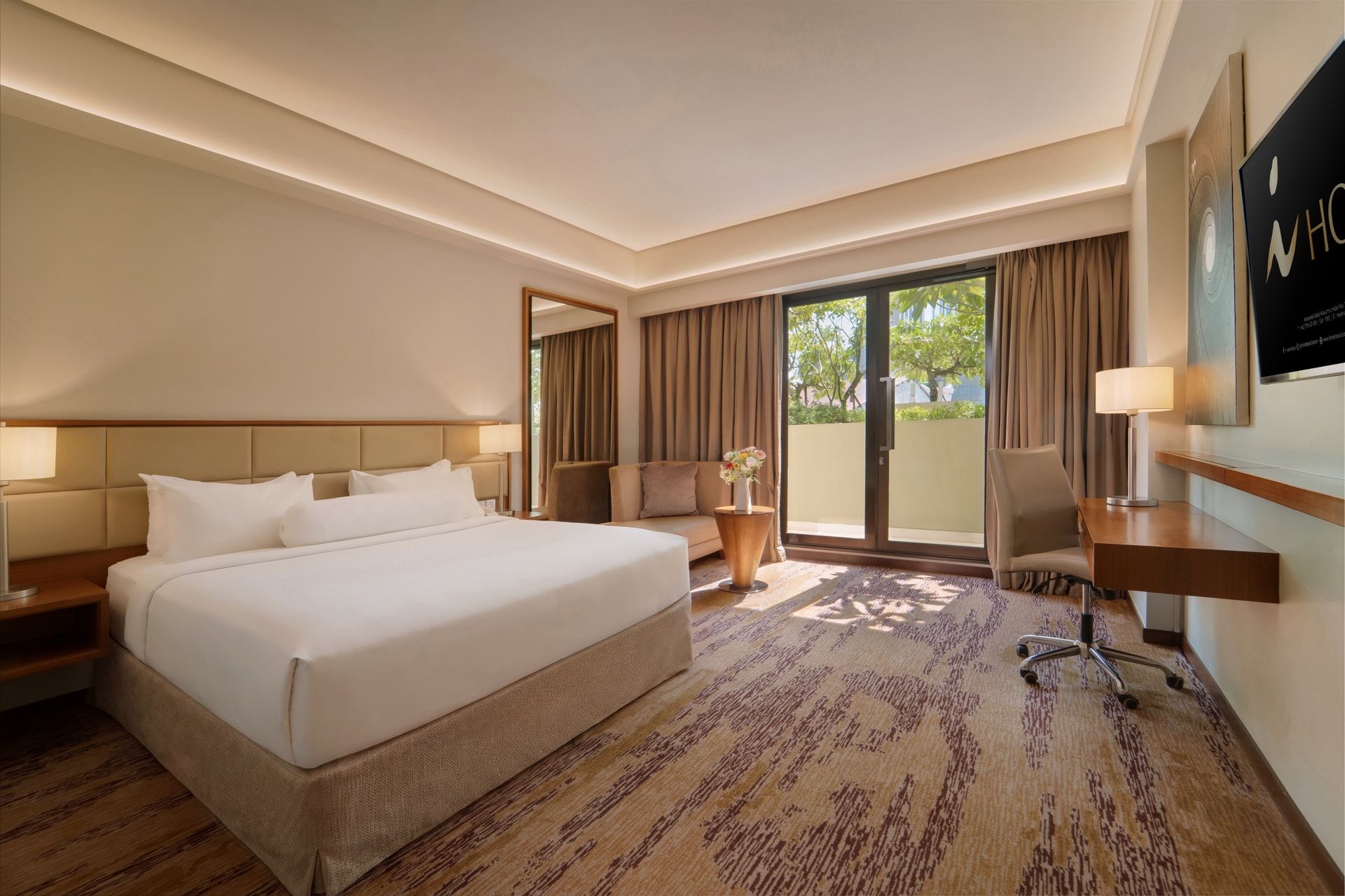 A hotel room with a large bed, a desk, a chair, a sofa, and a view of the outdoors.