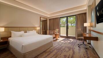 A hotel room with a large bed, a desk, a chair, a sofa, and a view of the outdoors.