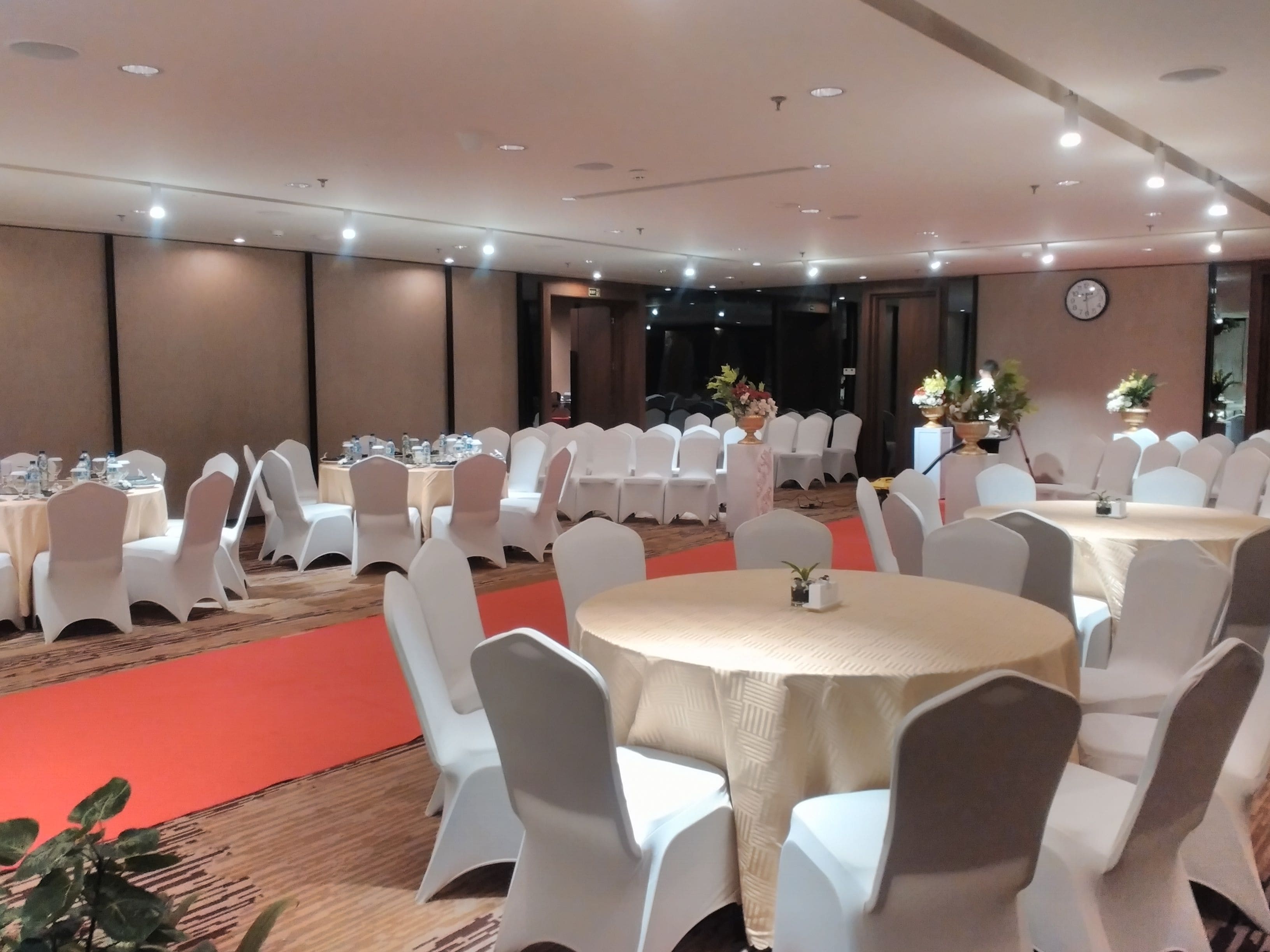 A conference room with round tables and white chairs, equipped with water bottles and nameplates.