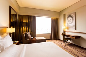 A hotel room with a bed, a desk, a chair, a lamp, a mirror, and a window with curtains. - I Hotel Baloi Batam (Batam)