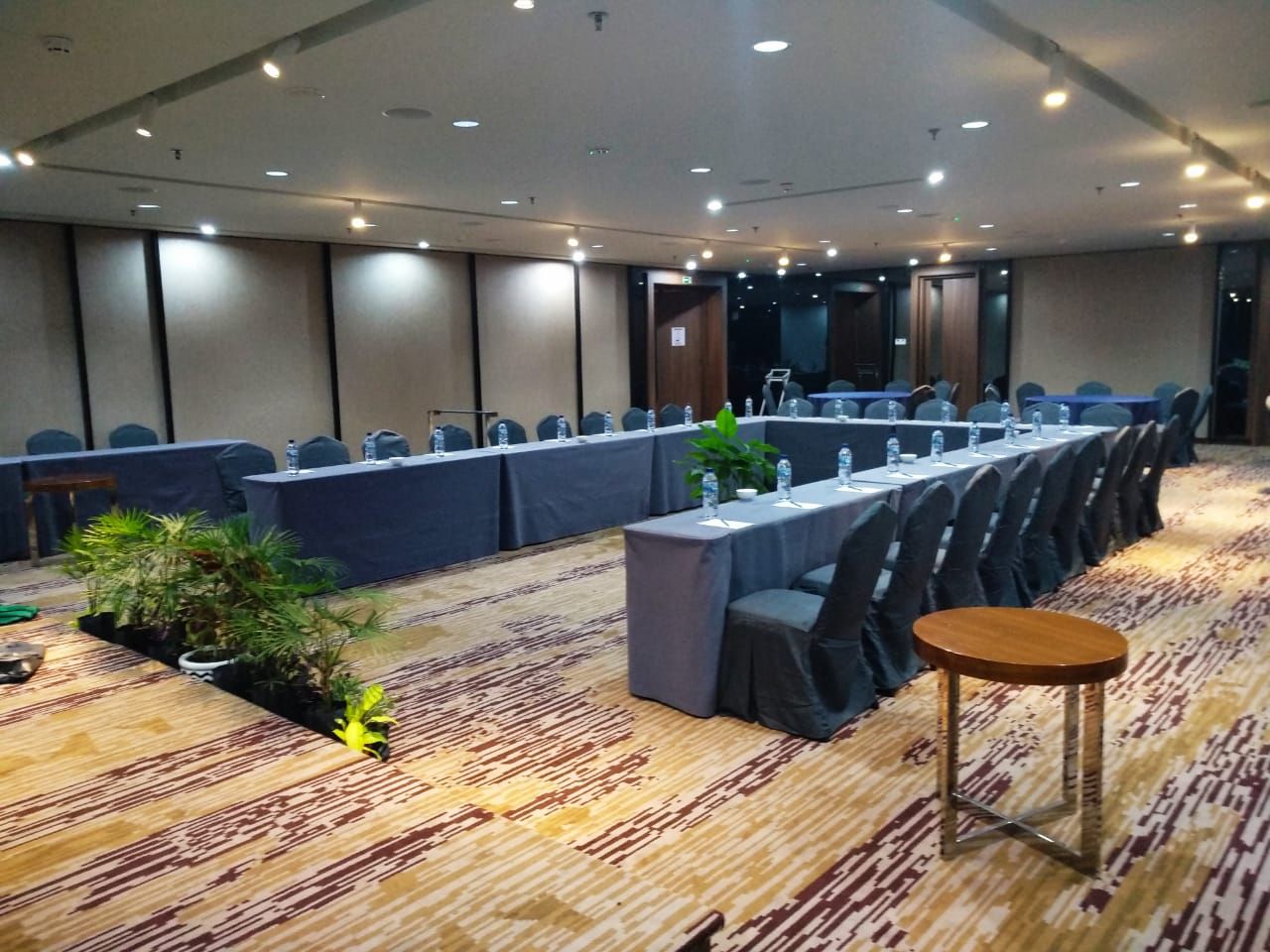 Une salle de conférence avec de longues tables, des chaises et une petite table ronde.