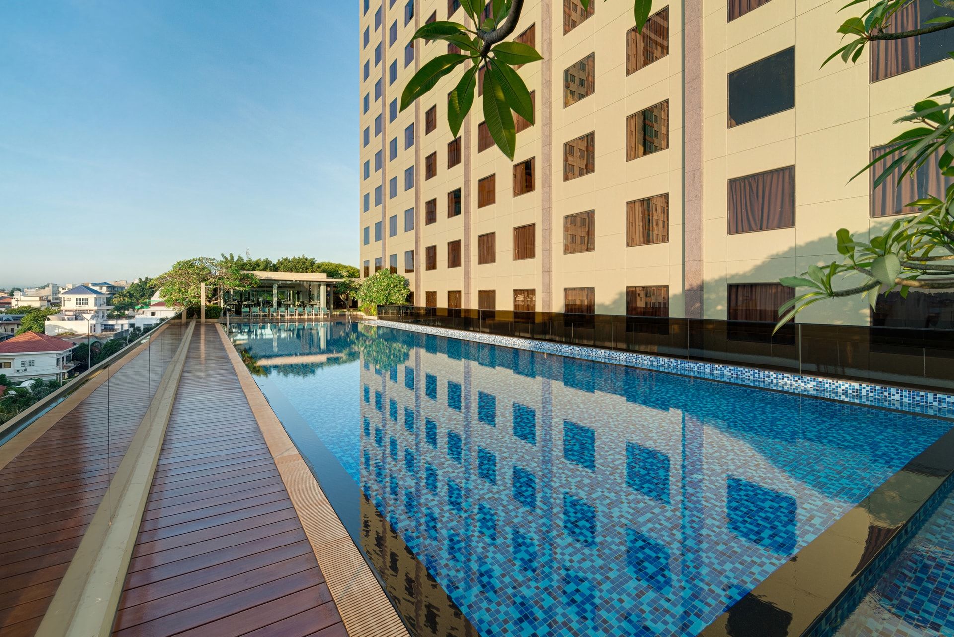 A rooftop swimming pool with a tiled floor, surrounded by a wooden deck.