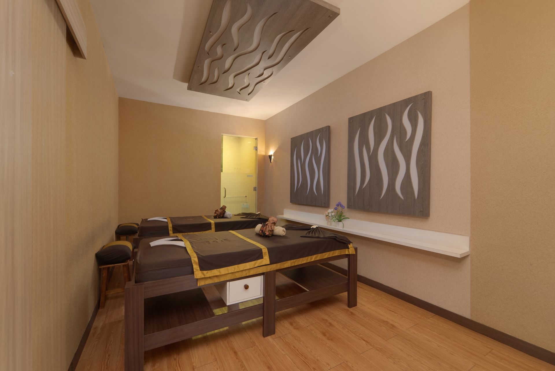 Une salle de spa équipée d’une table de massage, d’œuvres d’art accrochées au mur et d’un plancher en bois.