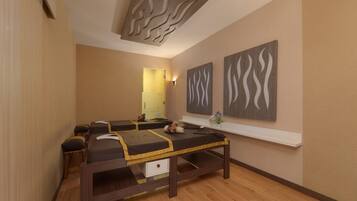 Une salle de spa équipée d’une table de massage, d’œuvres d’art accrochées au mur et d’un plancher en bois.