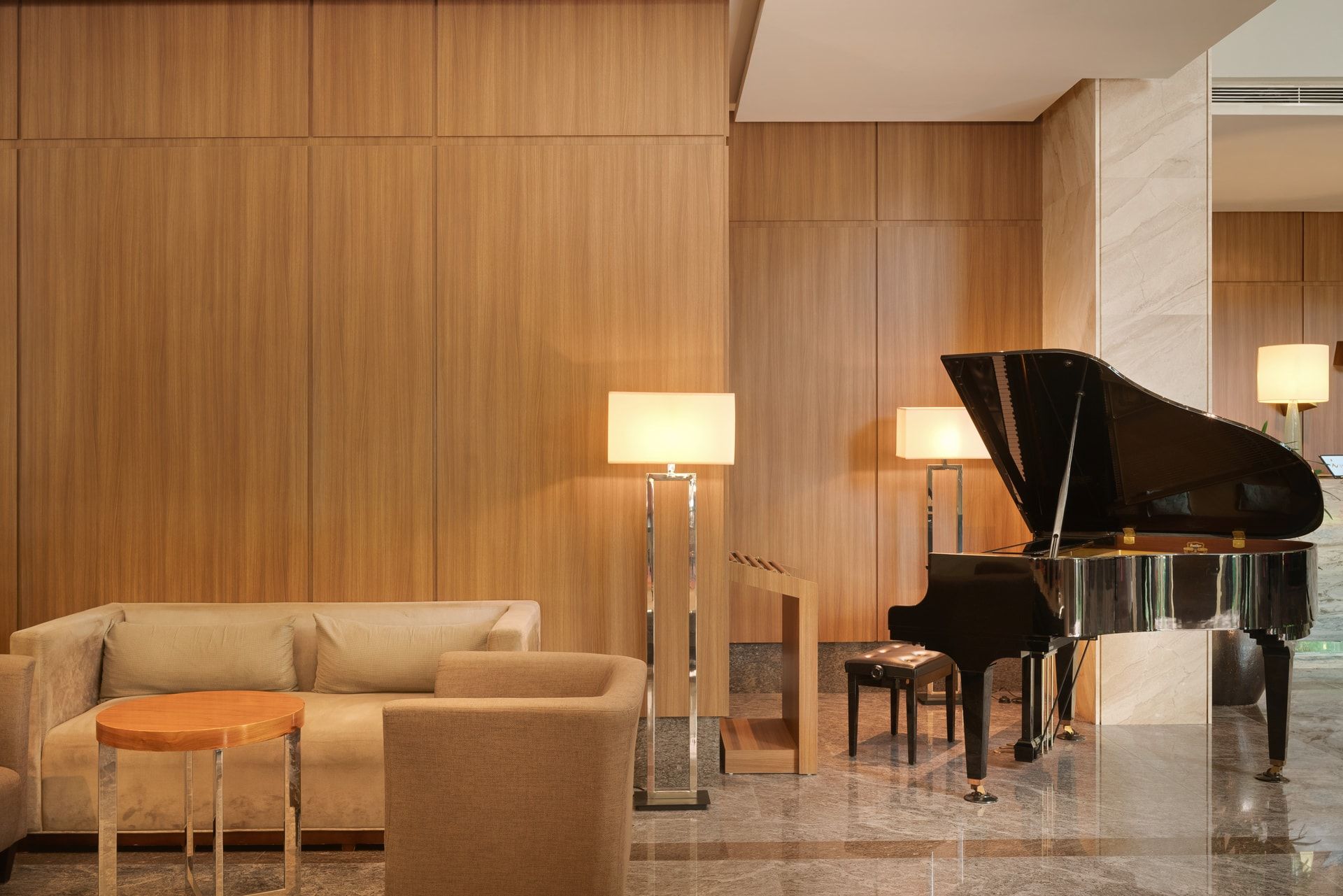 A modern lobby with a grand piano, a sofa, and a floor lamp.