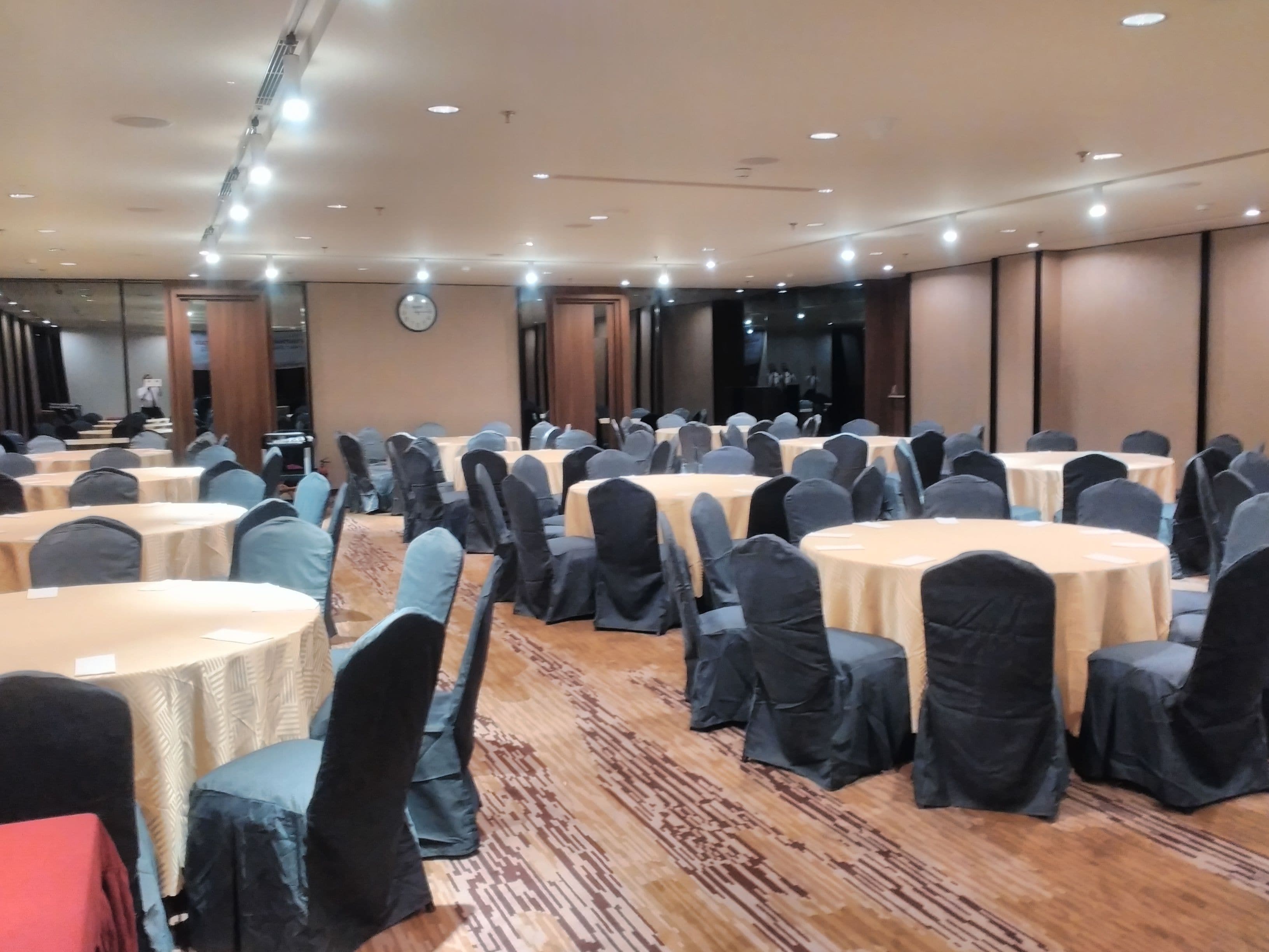 Un salón de conferencias con mesas redondas, sillas y un escenario.