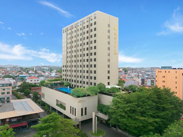 Un hotel de gran altura con varios pisos, una piscina en la azotea y vistas de la ciudad circundante.