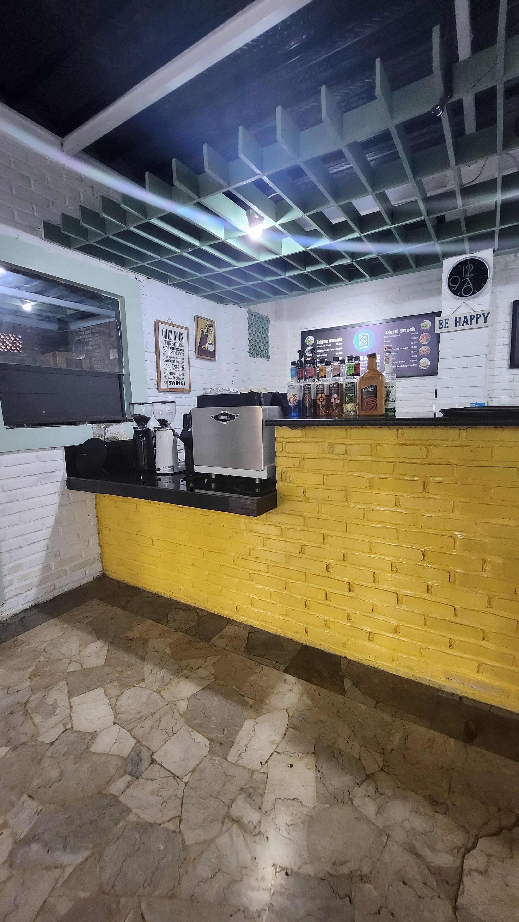 A cafe interior with a coffee machine, a menu board, and a clock on the wall.