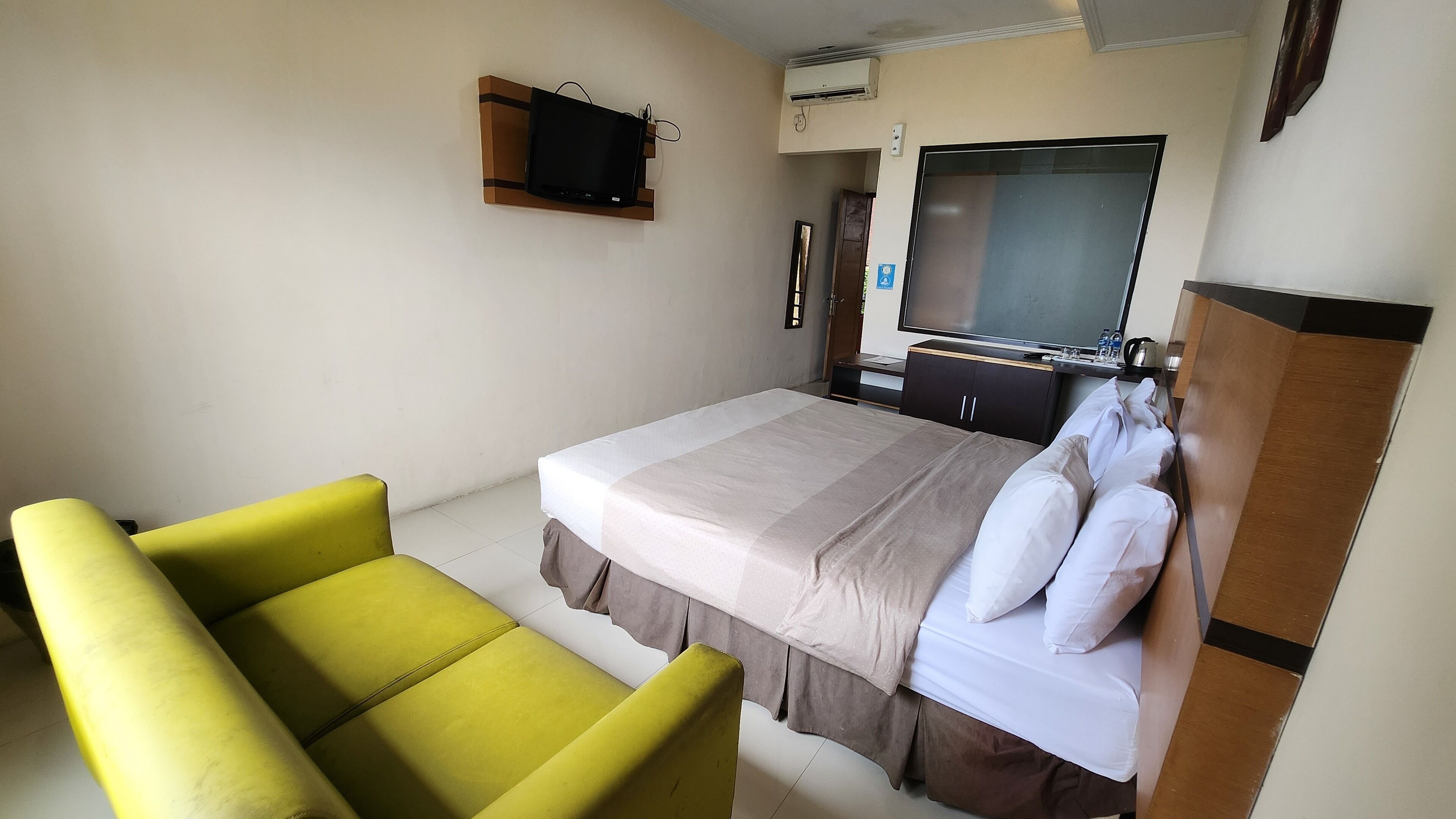 A hotel room with a bed, a television, and a desk.