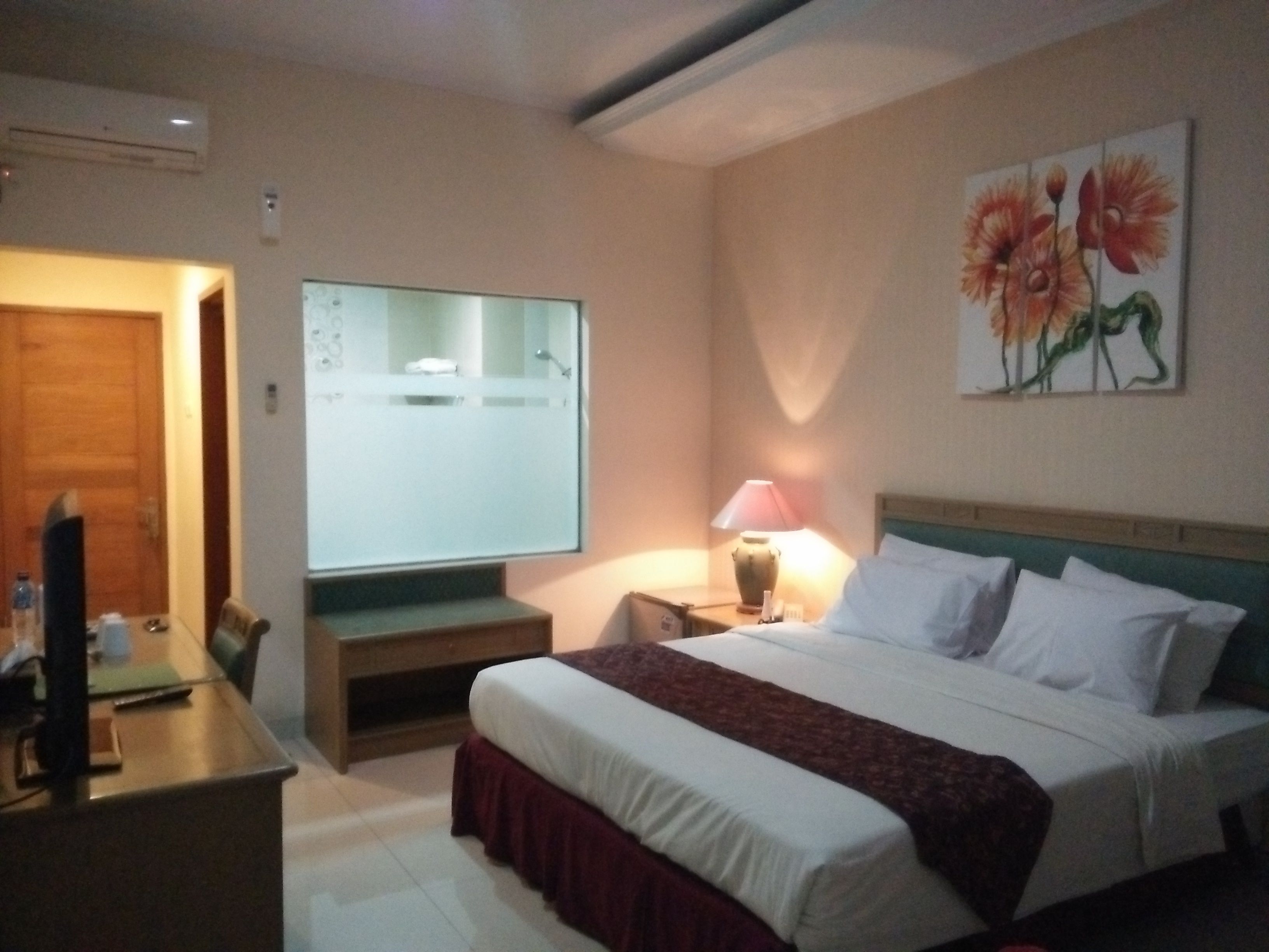 Une chambre d’hôtel avec un lit, une table de chevet, une lampe et un tableau au mur.