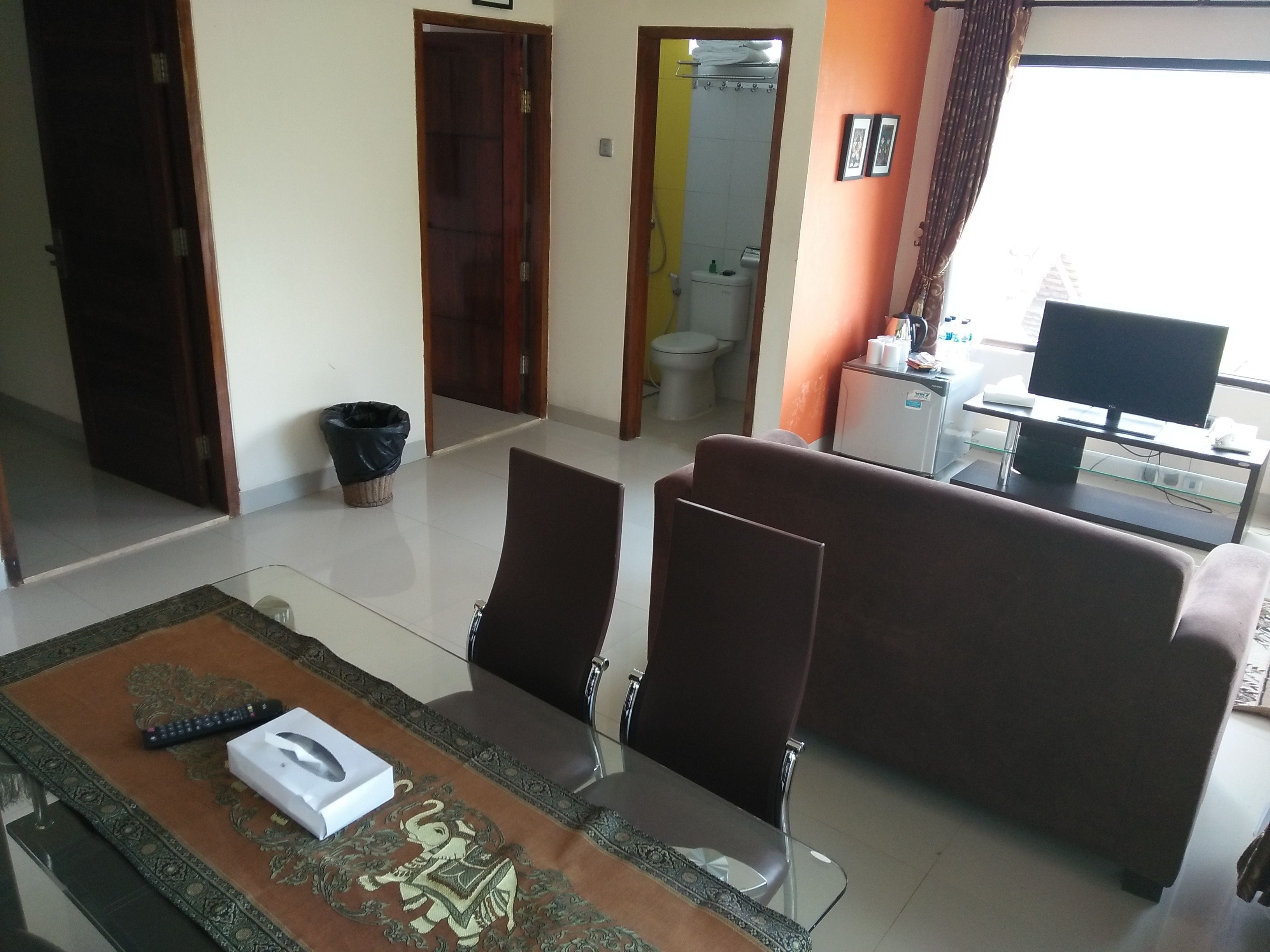 A living room with a sofa, a glass coffee table, and a TV on a stand.
