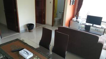 A living room with a sofa, a glass coffee table, and a TV on a stand.