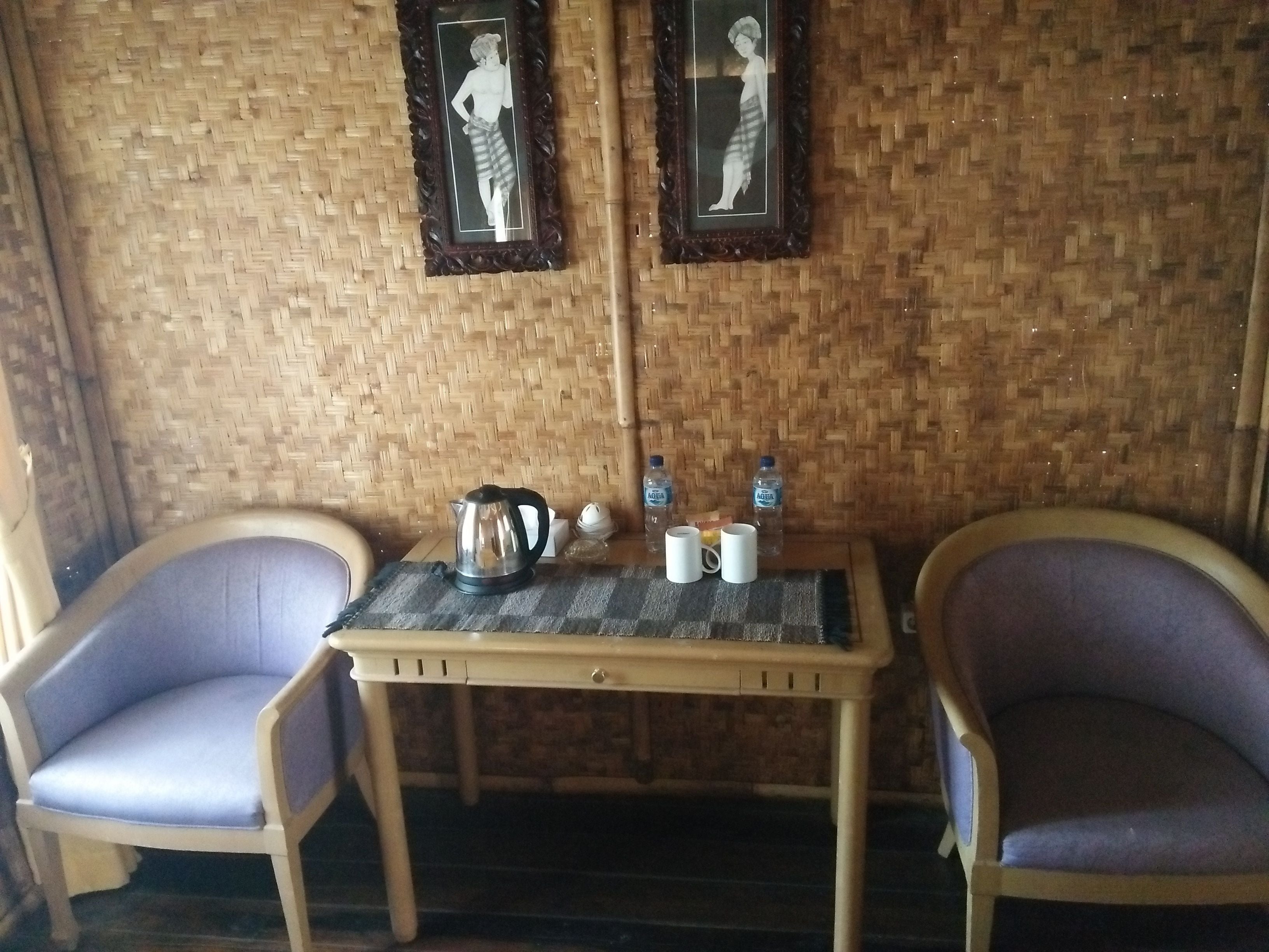 A room with two chairs, a table, a kettle, two water bottles, and two cups.