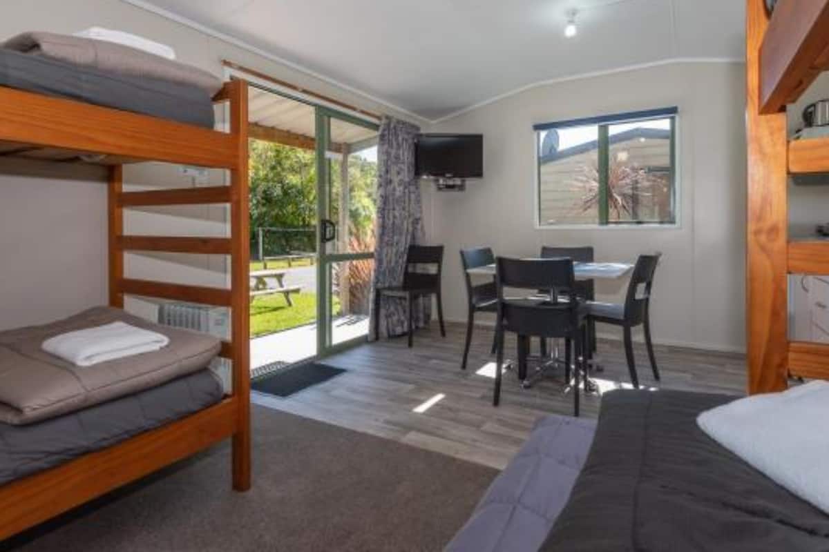 Une chambre avec des lits superposés, un bureau, des chaises et un téléviseur.