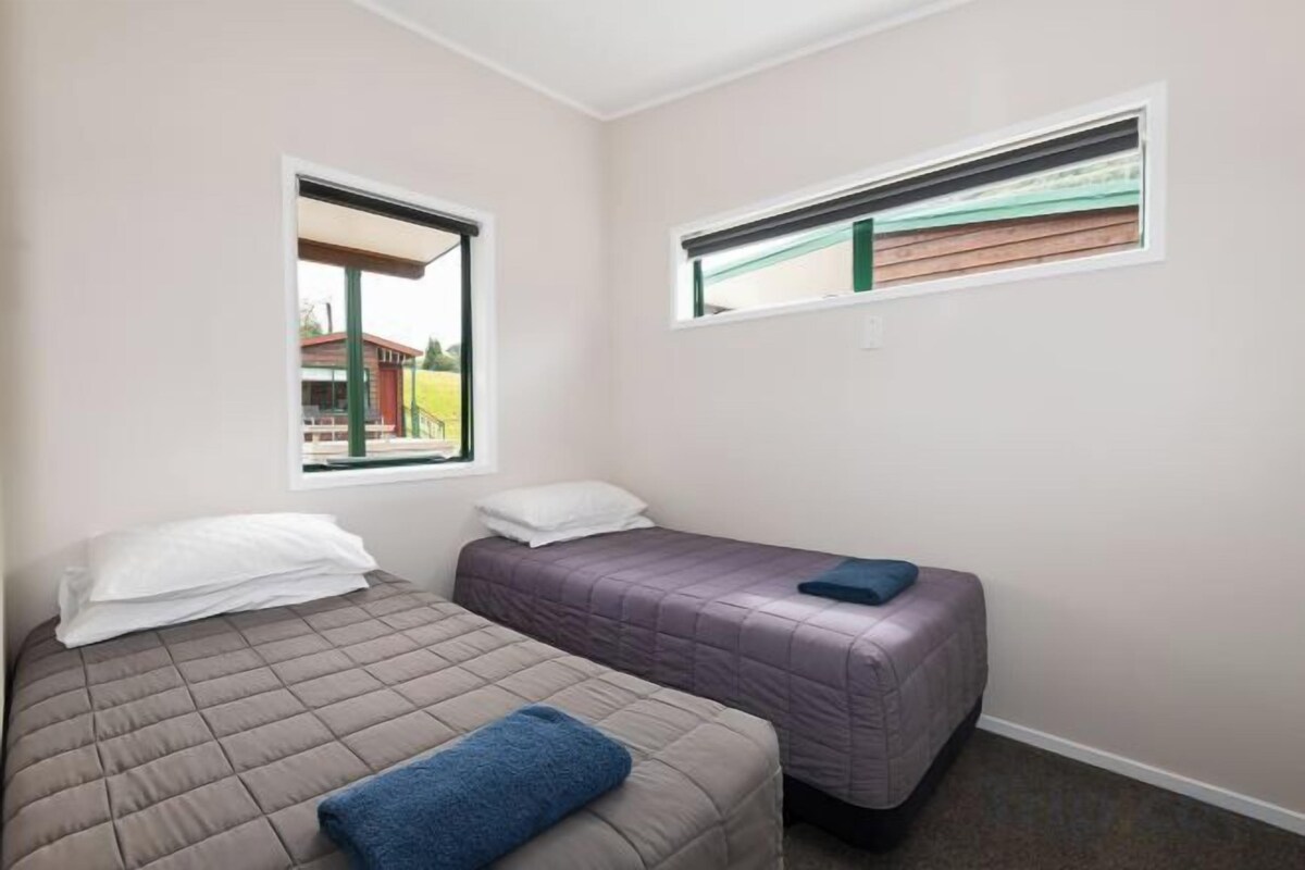 A bedroom with two beds, a window, and a view of a building outside.