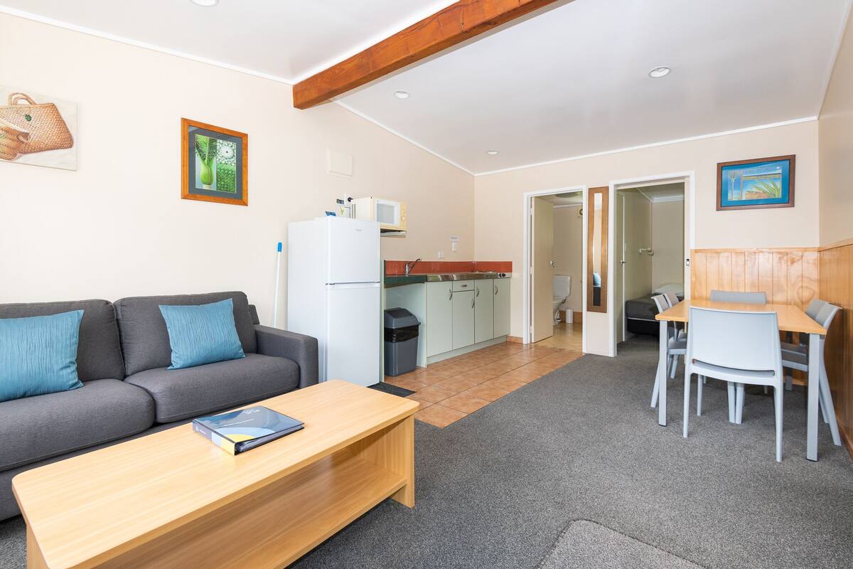 Un salon moderne comprenant un canapé, une table basse et un coin repas avec une table et des chaises.