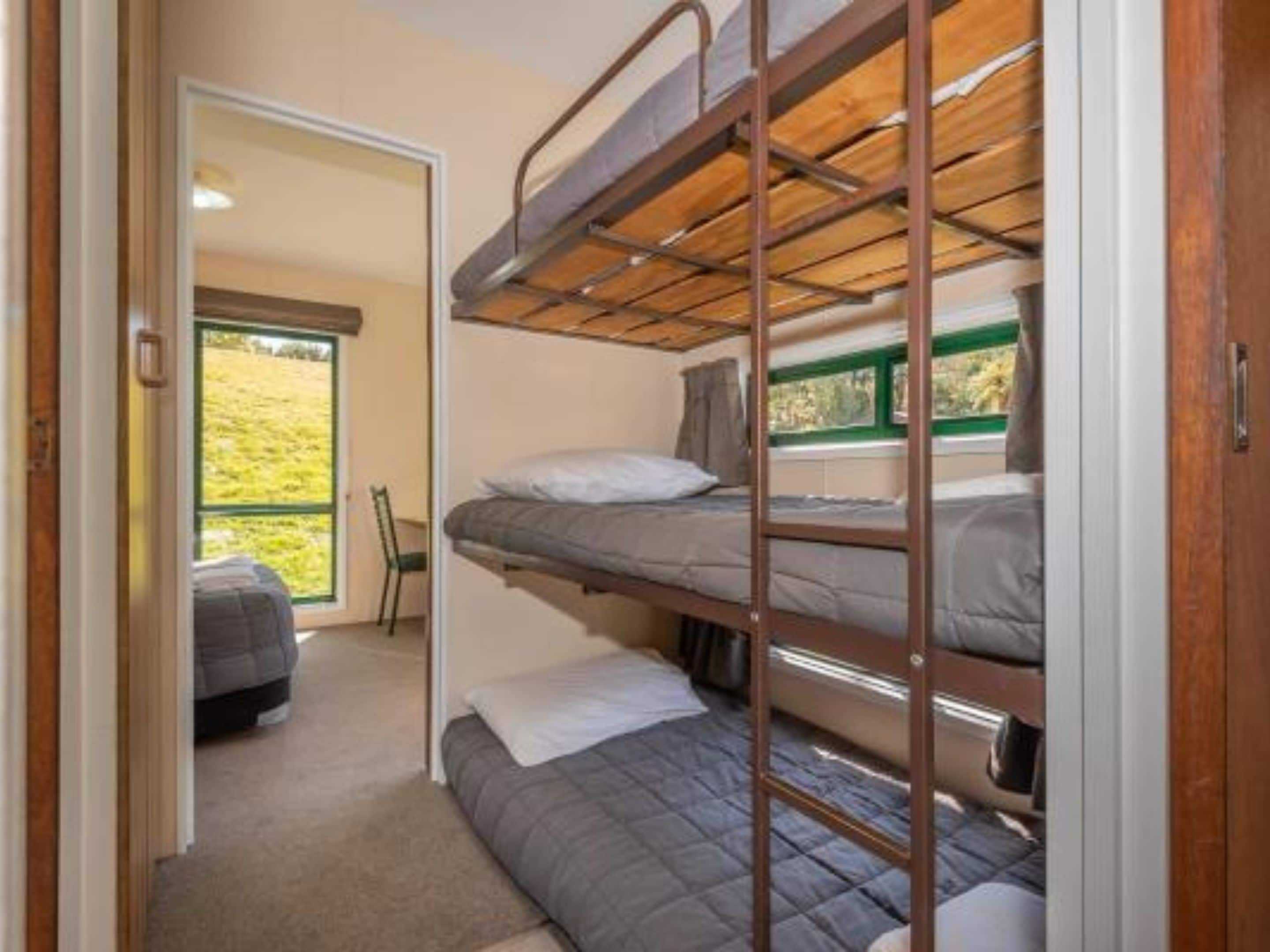 Dormitorio con literas, ventana, puerta que da a otra habitación y vistas a un espacio exterior.