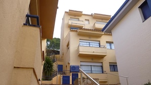 Une ruelle étroite avec un escalier menant à un immeuble à plusieurs étages doté de balcons.