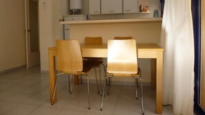 Ein Essbereich mit einem Holztisch und vier Stühlen, einer weißen Decke und einer weißen Wand.